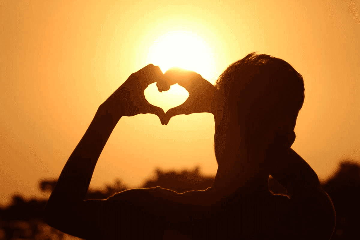 Person forming a heart shape with their hands at sunset, symbolizing heart health