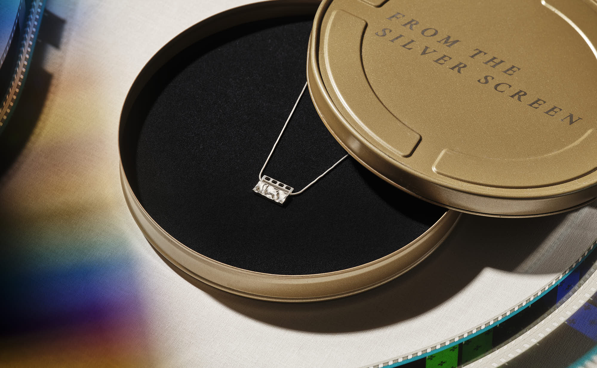 Silver necklace in a gold film reel tin with "From the Silver Screen" text.
