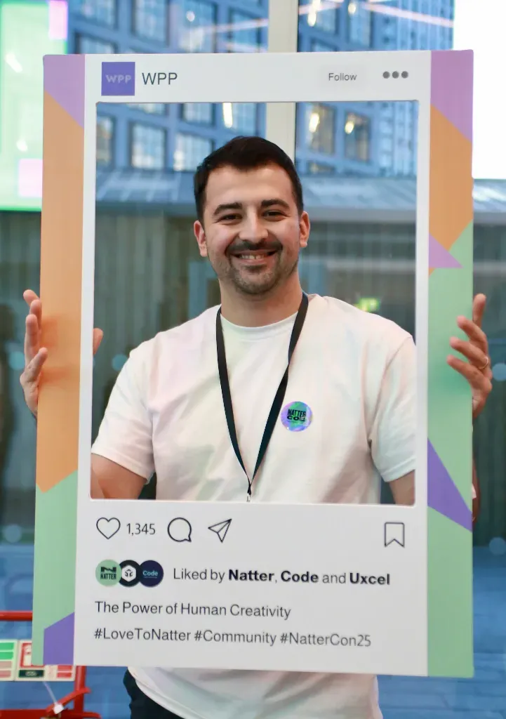 A man holding a large Instagram-style frame with a photo of himself inside.