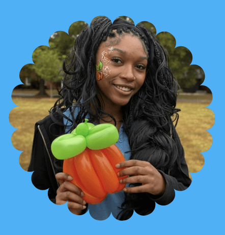 Shayne smiling and holding a balloon palm tree and balloon monkey