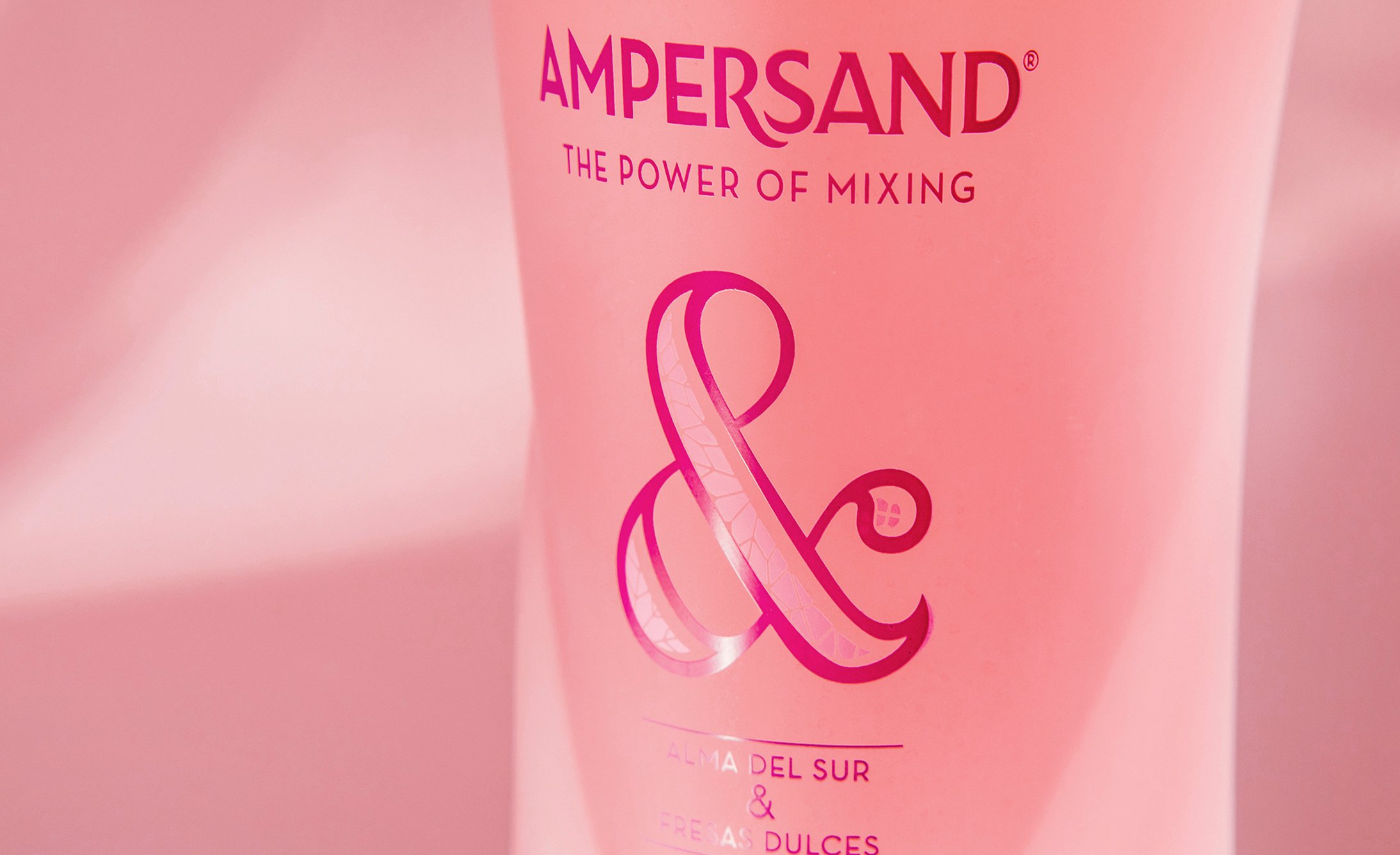 A pink bottle with the label "Ampersand: The Power of Mixing." Features a prominent decorative ampersand symbol. The tone is modern and elegant.
