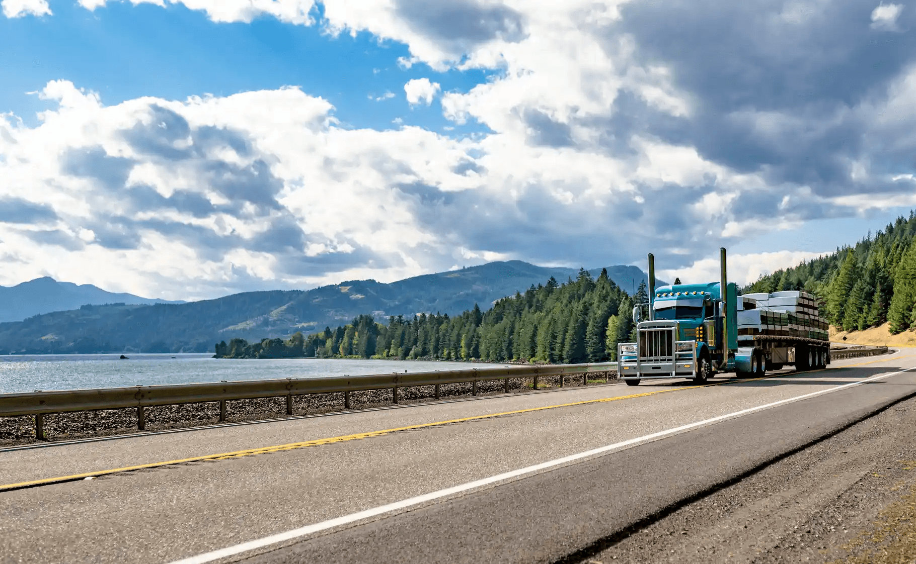 Semi-truck hauling freight through a mountain highway under a cloudy sky, symbolizing GIA Group, LLC clients’ success stories and reliable trucking coverage.