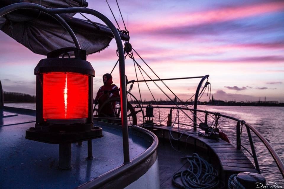 A ship's red lantern at dusk over the water