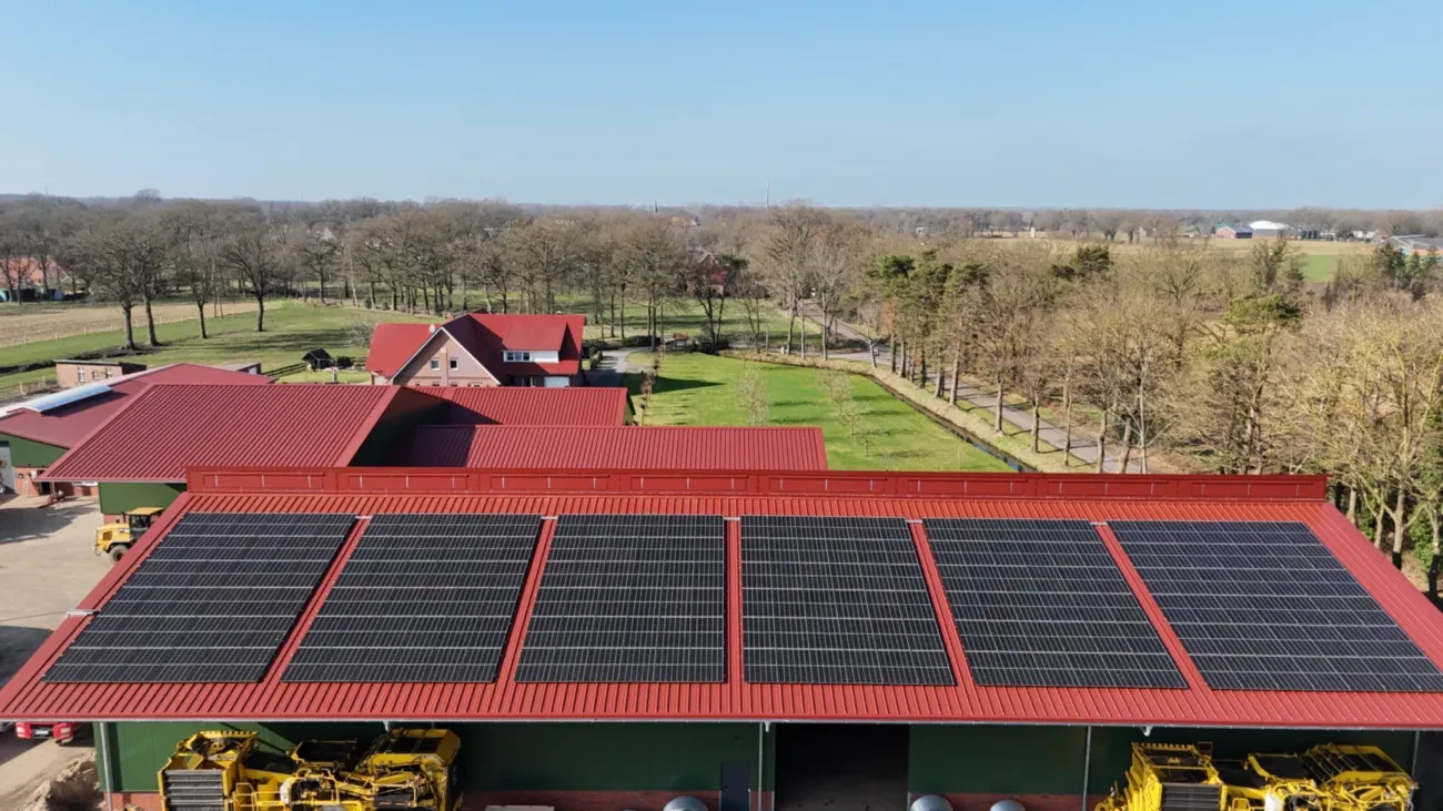 Luftaufnahme eines Bauernhofs mit Biogasanlage, Solaranlagen und Feldern.