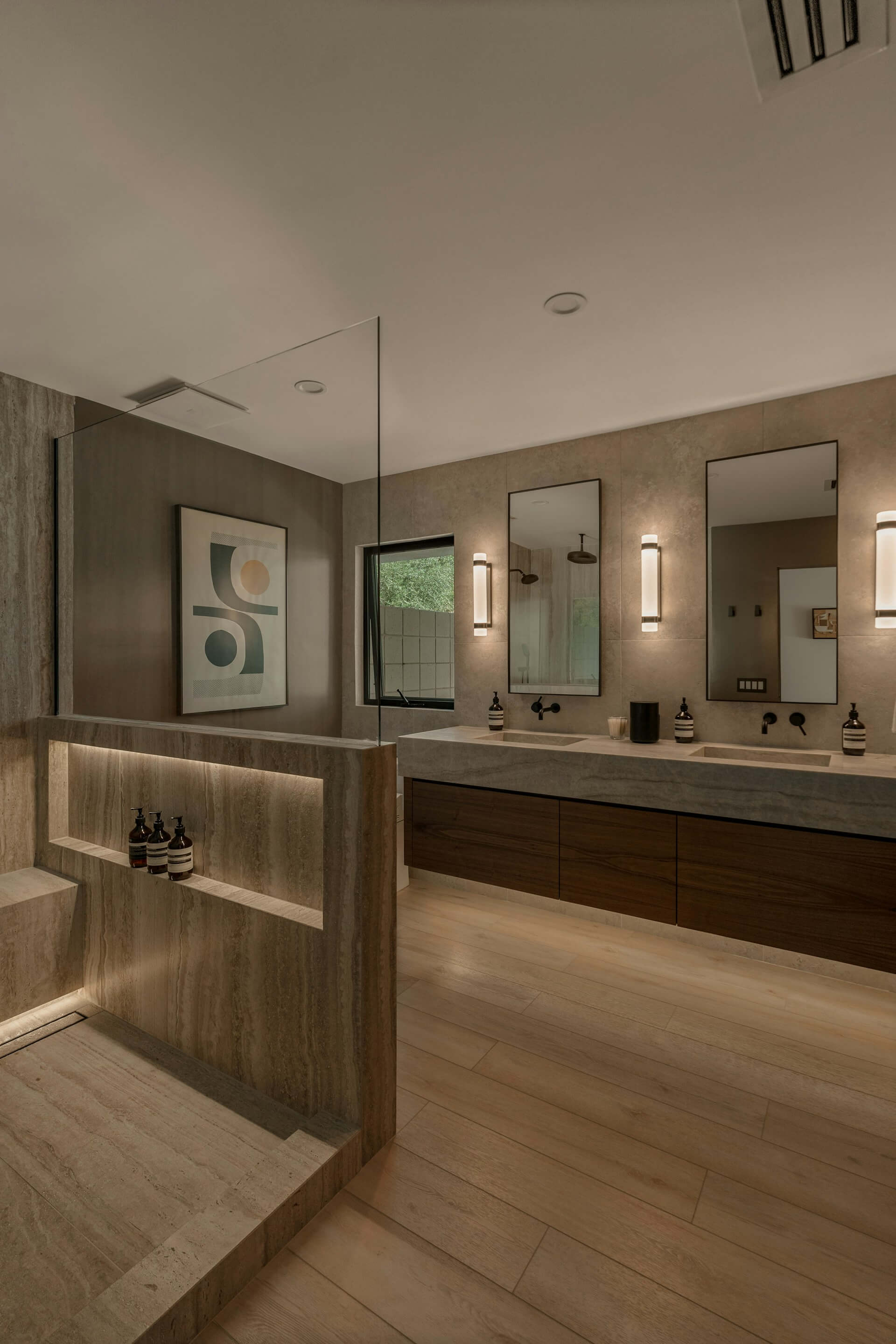 Luxury modern bathroom with travertine stone walls and floating walnut vanity.
