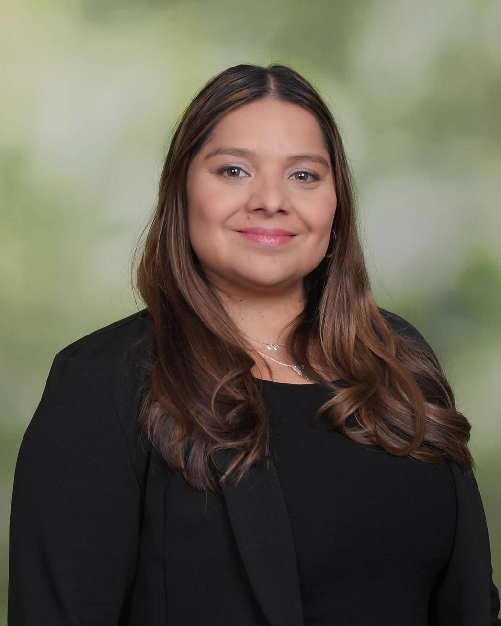 Smiling female therapist with short gray hair, wearing a brown top and a purple shawl, surrounded by a cozy background.