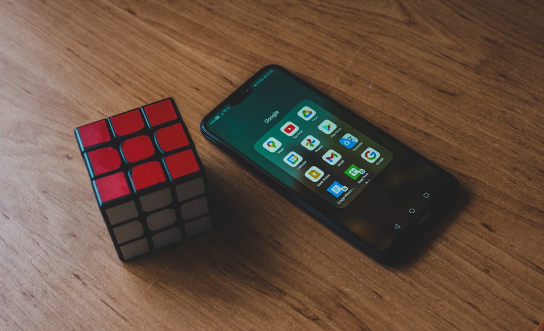 a cell phone sitting next to a rubik cube