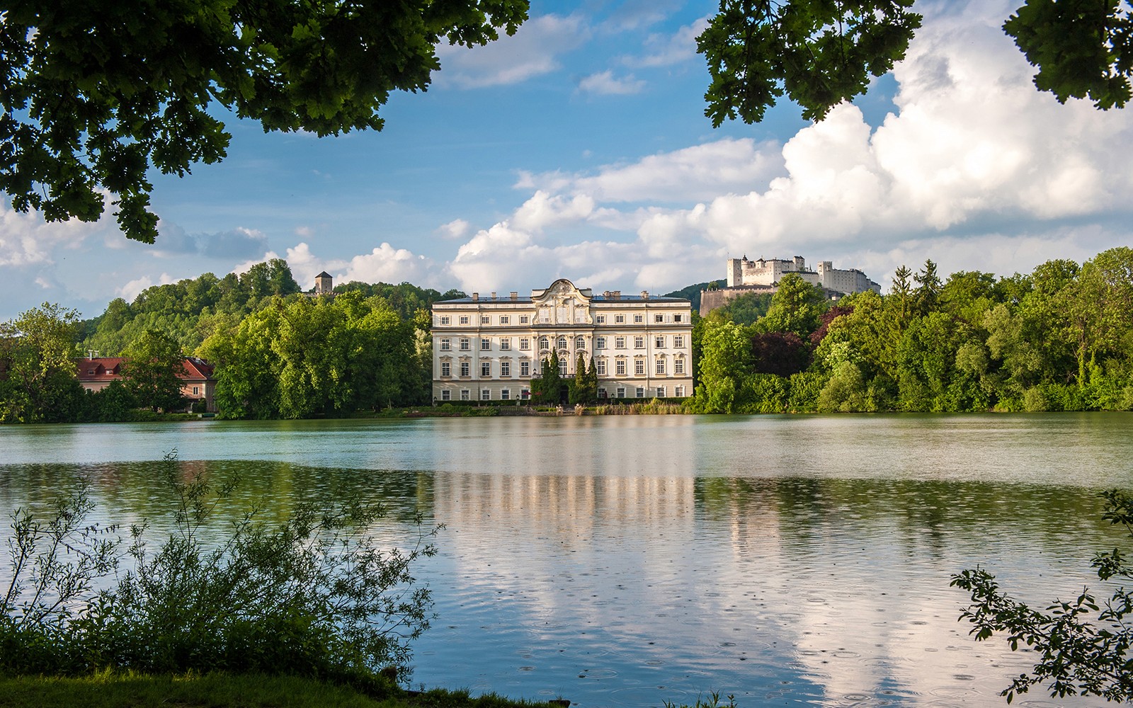Schloss Leopoldskron ved en sø med Hohensalzburg-fæstningen i Salzburg.