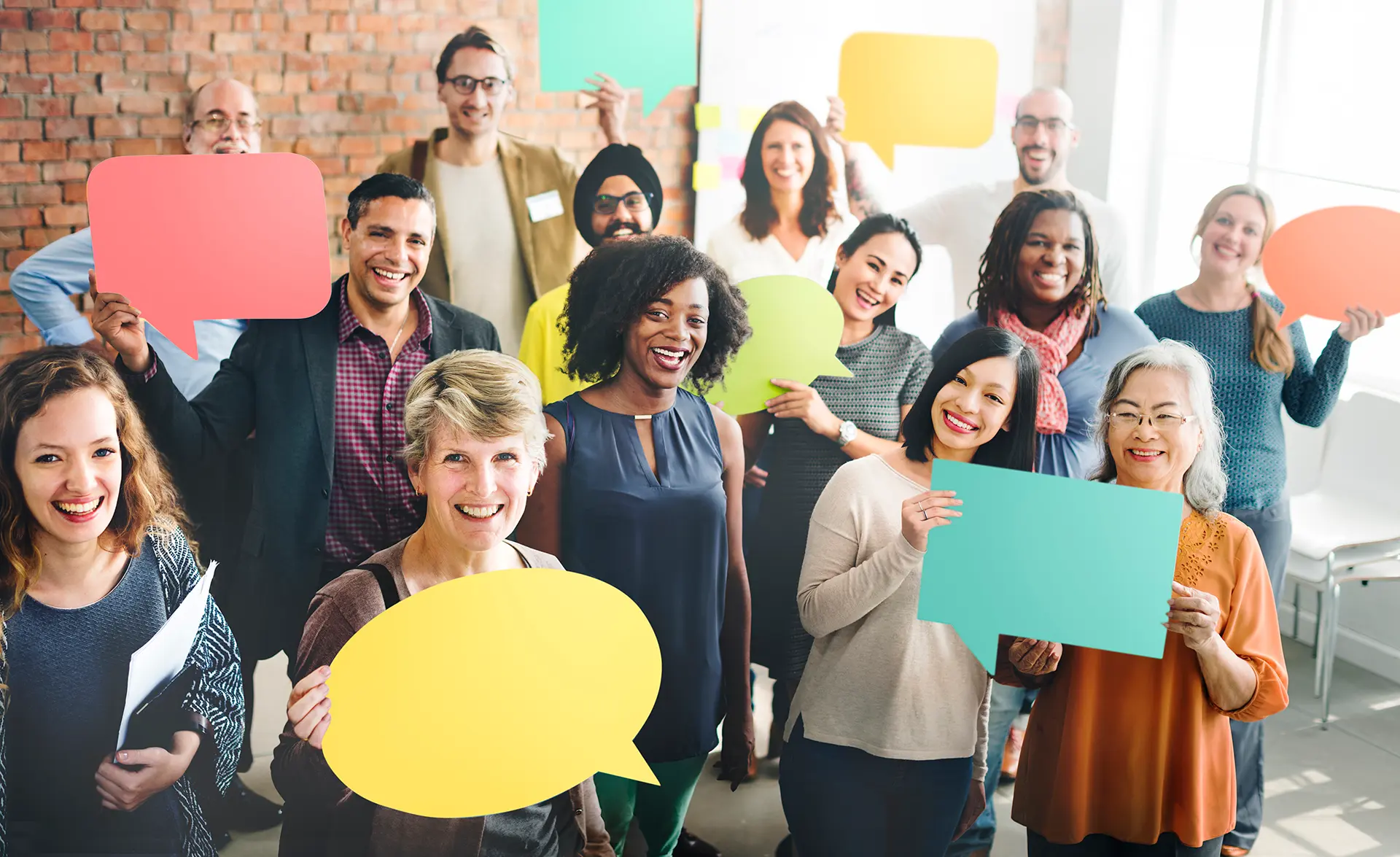 Smiling diverse group holding colourful speech bubble cut-outs, representing open communication and varied perspectives