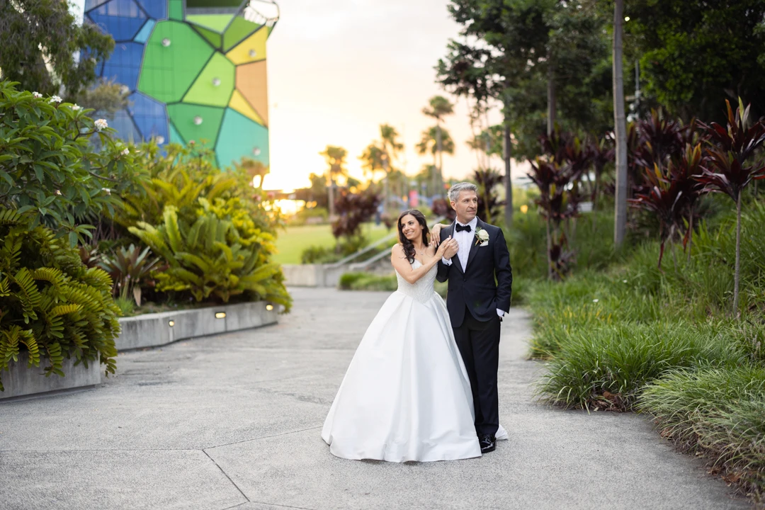 Bride and groom walking in garden at sunset
