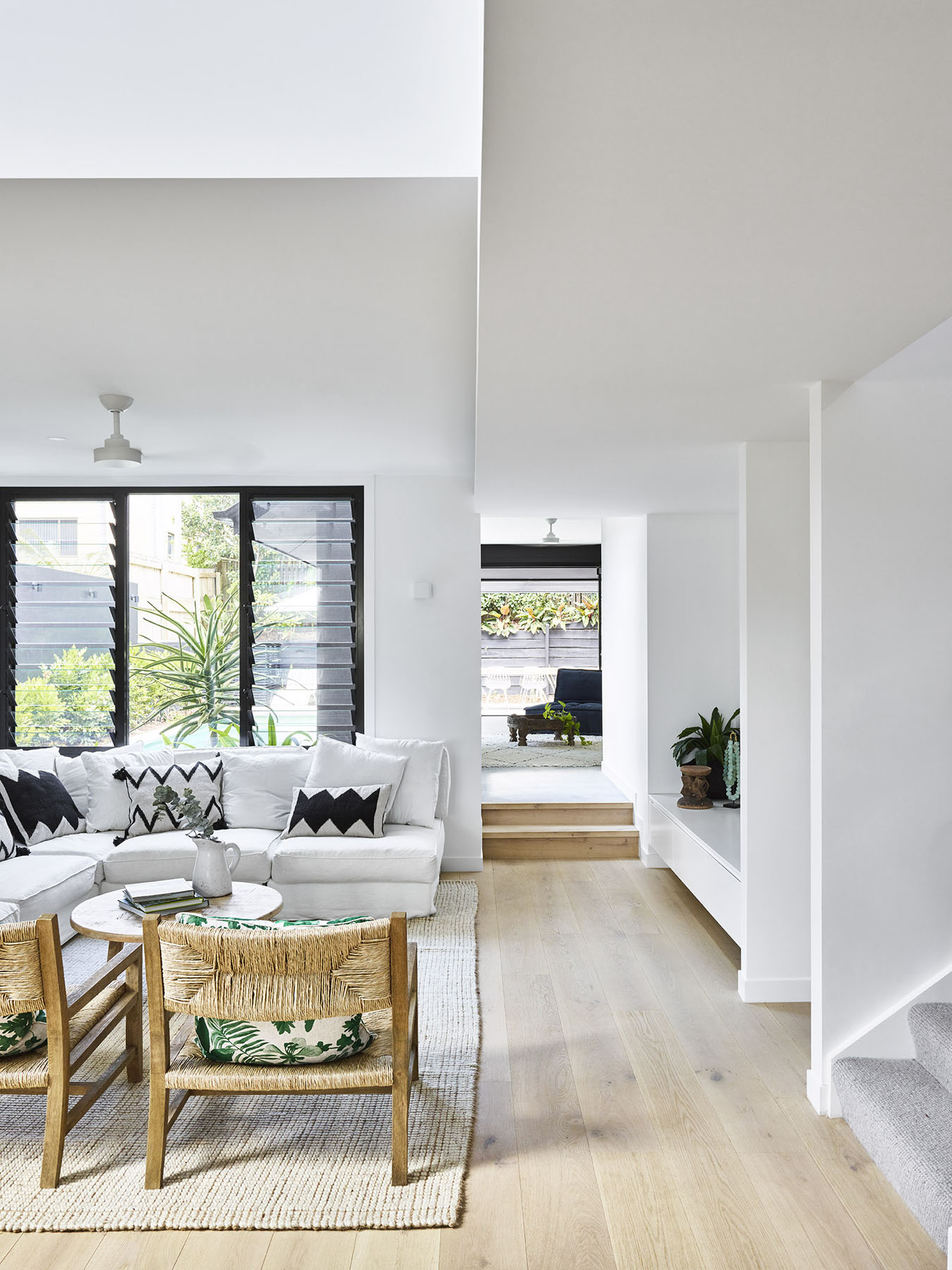 Open-plan living area with white interiors, timber floors, and indoor-outdoor flow.