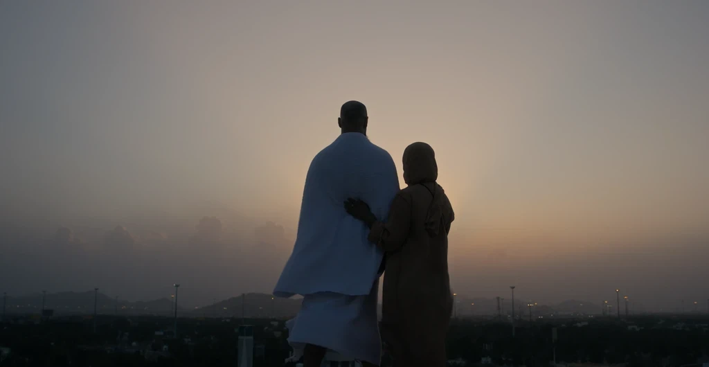 Two figures silhouetted by the rising sun