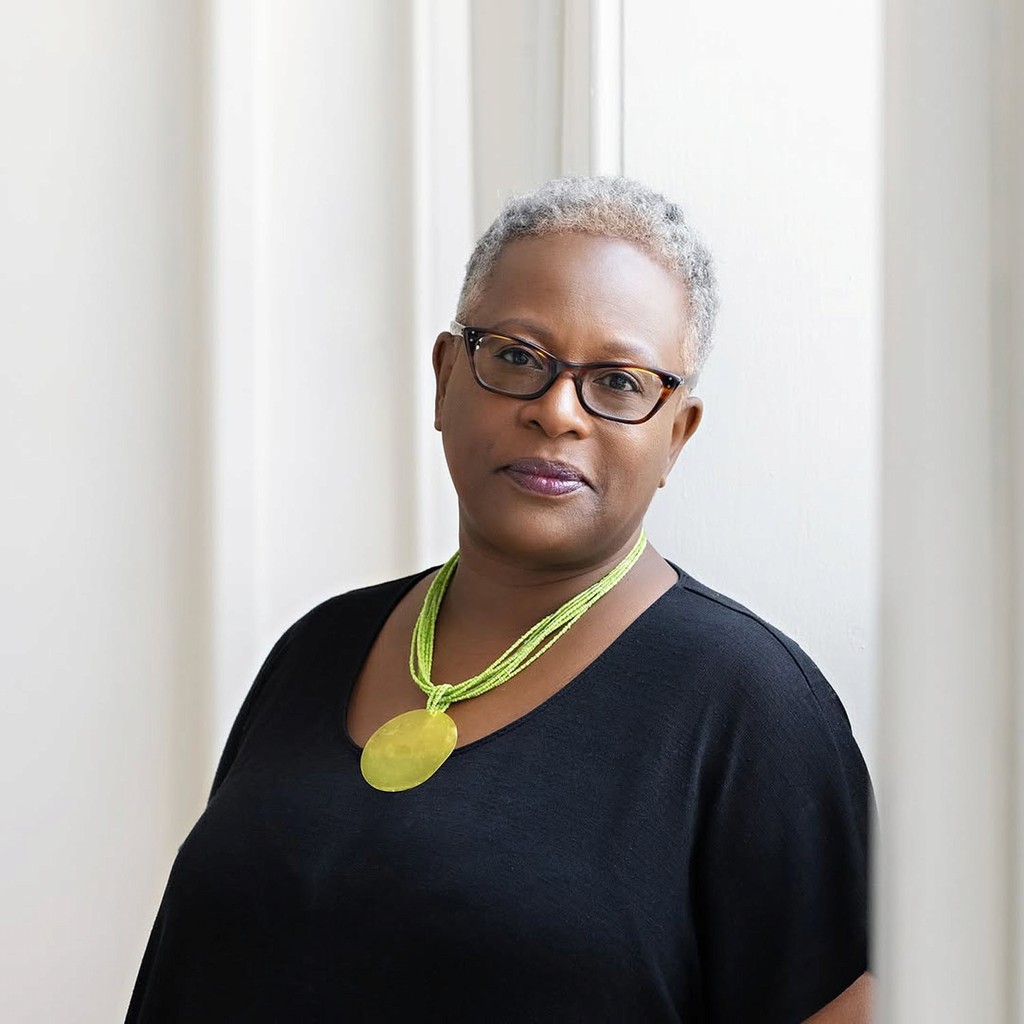 Elegant portrait taken at Node Studio, featuring a woman in a black top with a bold green necklace, framed by soft natural light streaming through large windows
