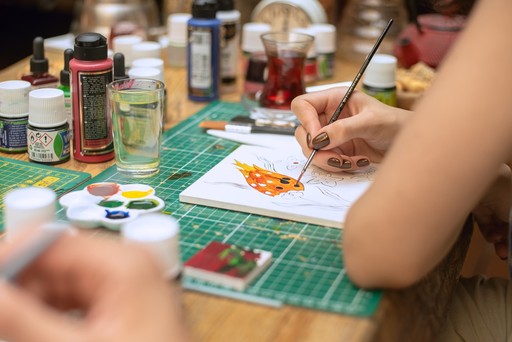 A close-up of hands painting a traditional Turkish tile design on a piece of ceramic during a workshop, showcasing the intricate art of tile painting in Istanbul.