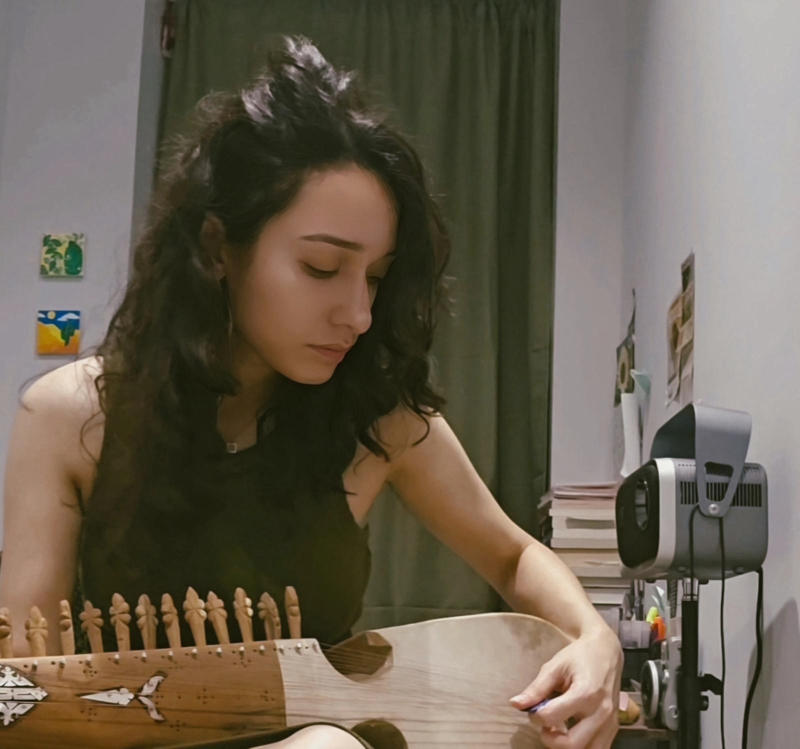 picture of team member hussain ahmed, wearing a turqoise fleece high neck sweater and glasses, smiling infront of the camera with thick fluffy black hair