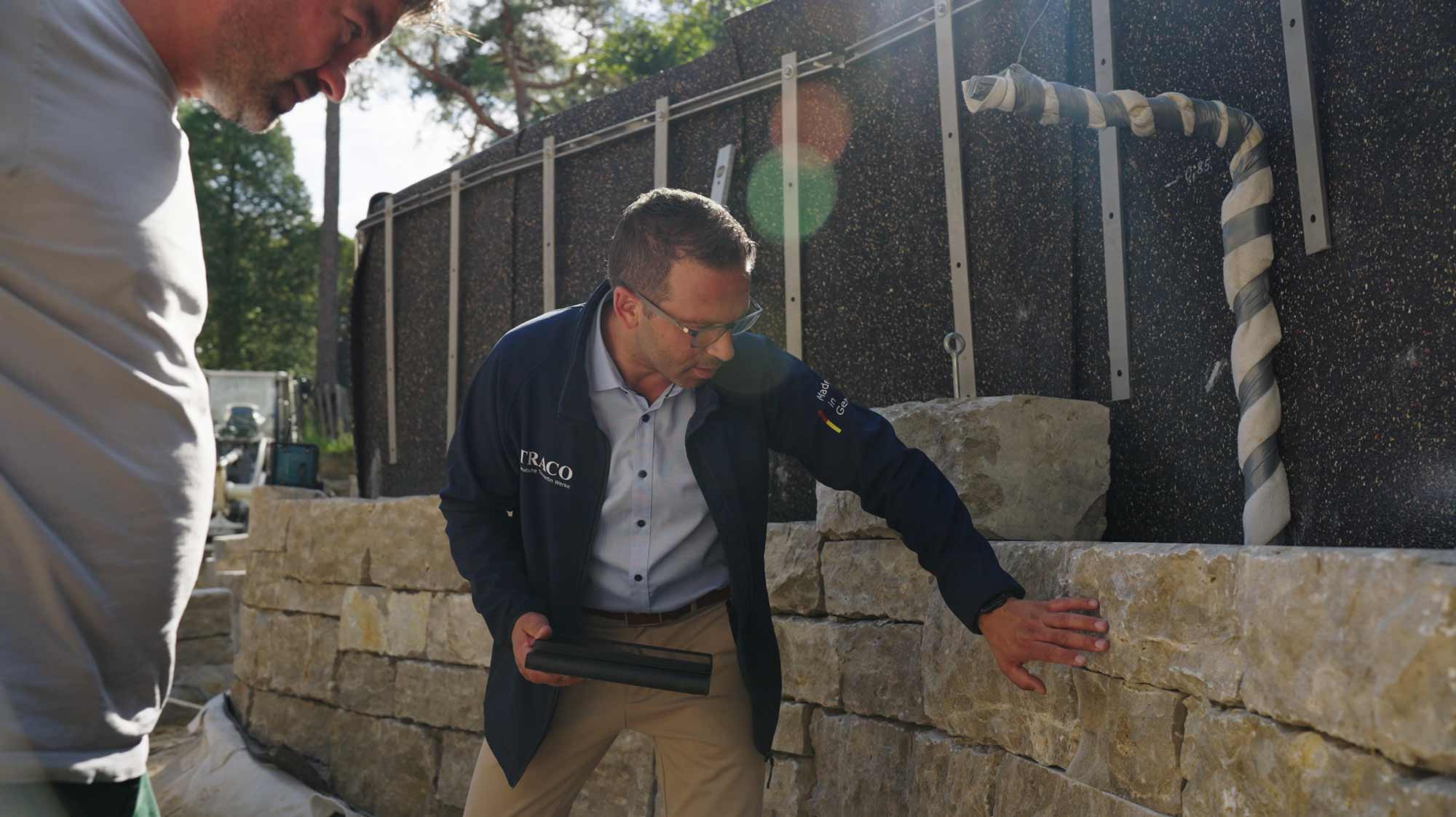 Man inspects stone wall, symbolizing strategic film production for advertising, storytelling, and social media campaigns.