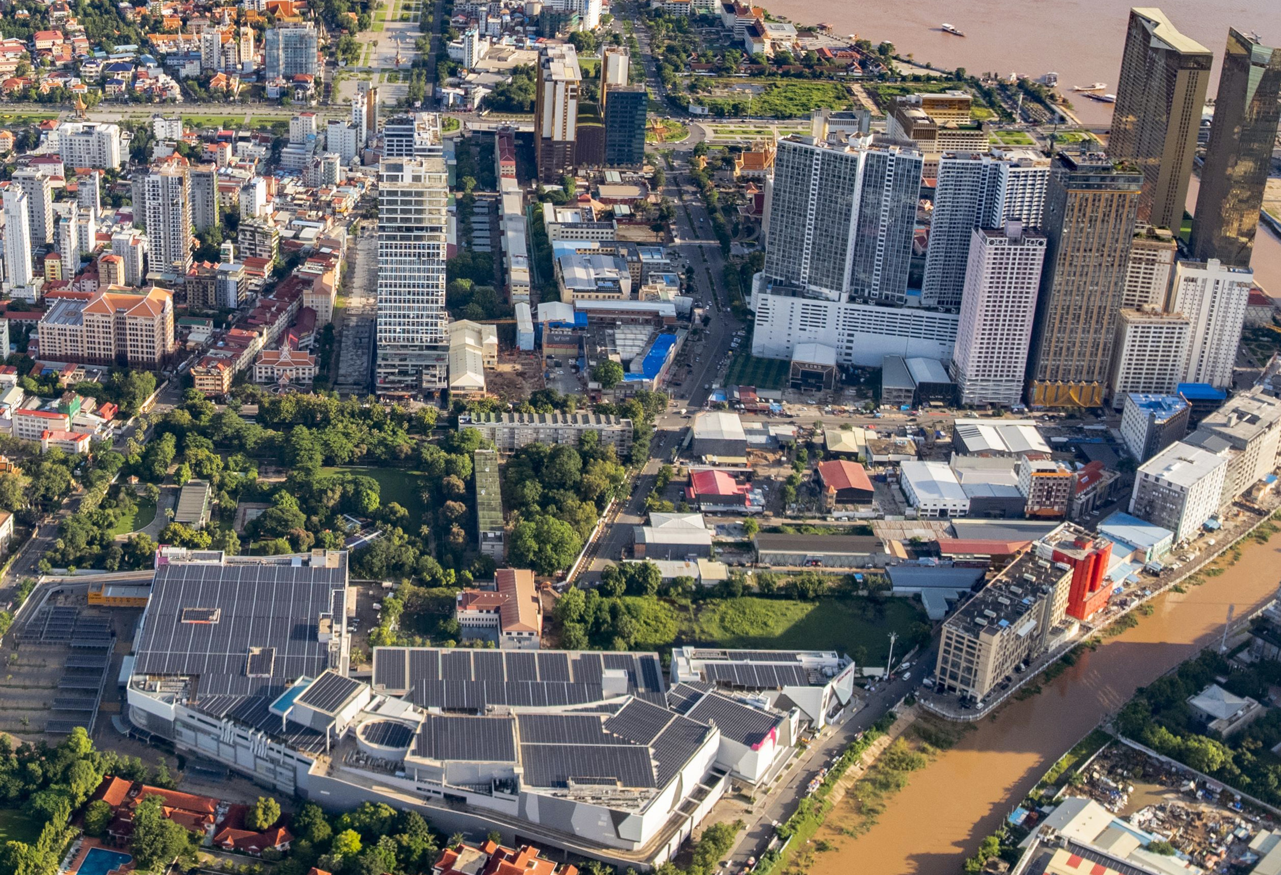Aerial view of Phnom Penh urban skyline showing dense commercial towers, retail developments, and residential neighborhoods along the riverfront