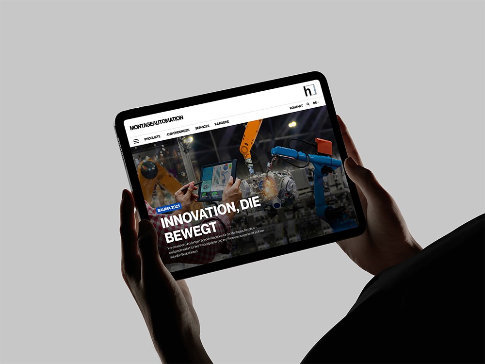 Person hält Tablet mit geöffneter Website eines Industrieunternehmens, das Roboter und Automationslösungen zeigt.