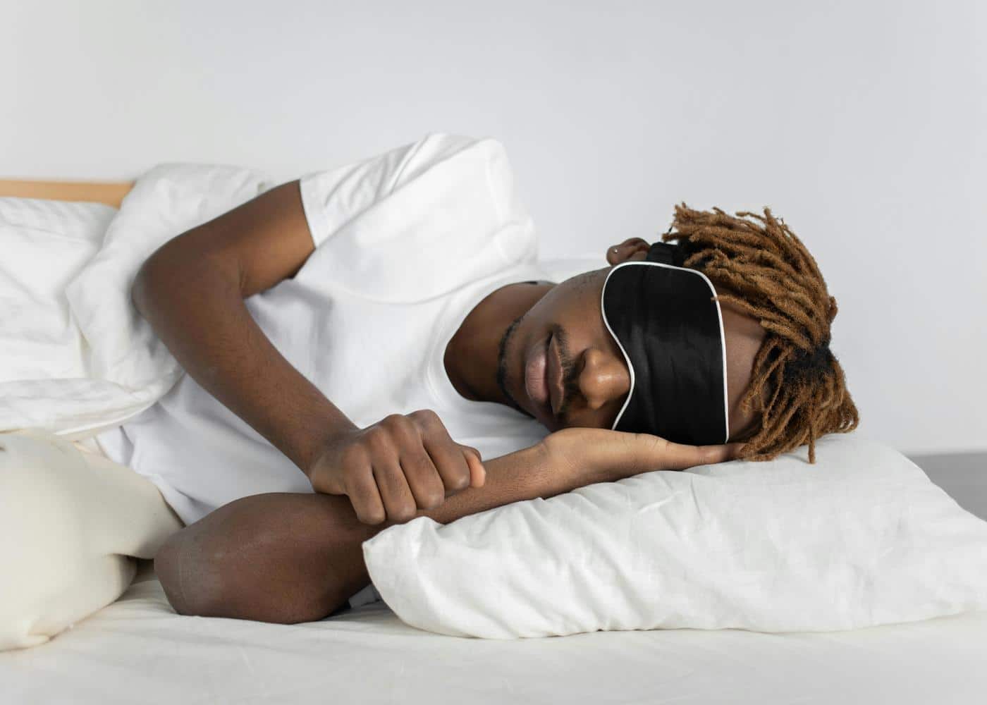 Man laying on bed trying to fall sleep with sleep mask on