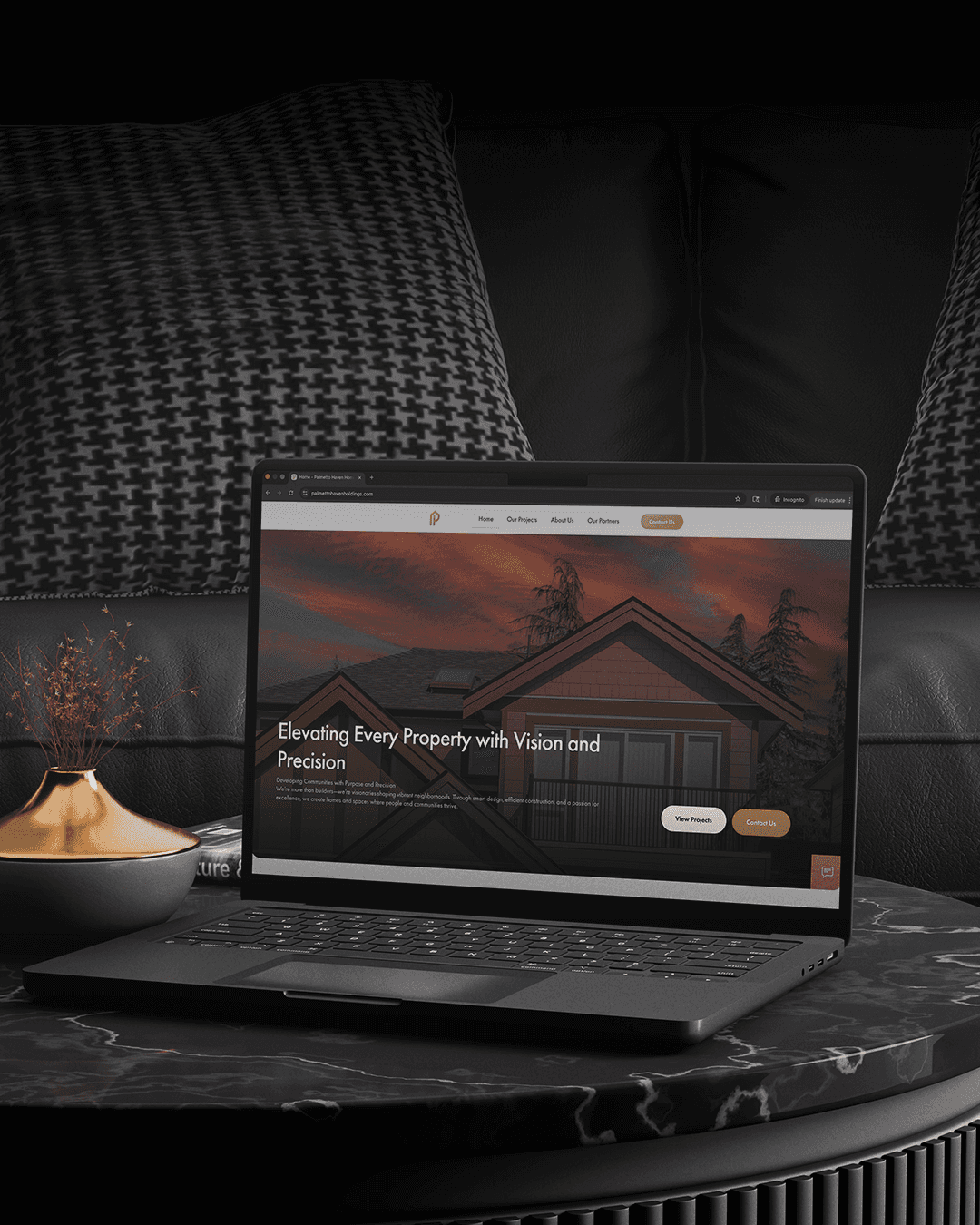 A laptop displaying a dark-themed website sits on a textured surface next to a small bowl of snacks.