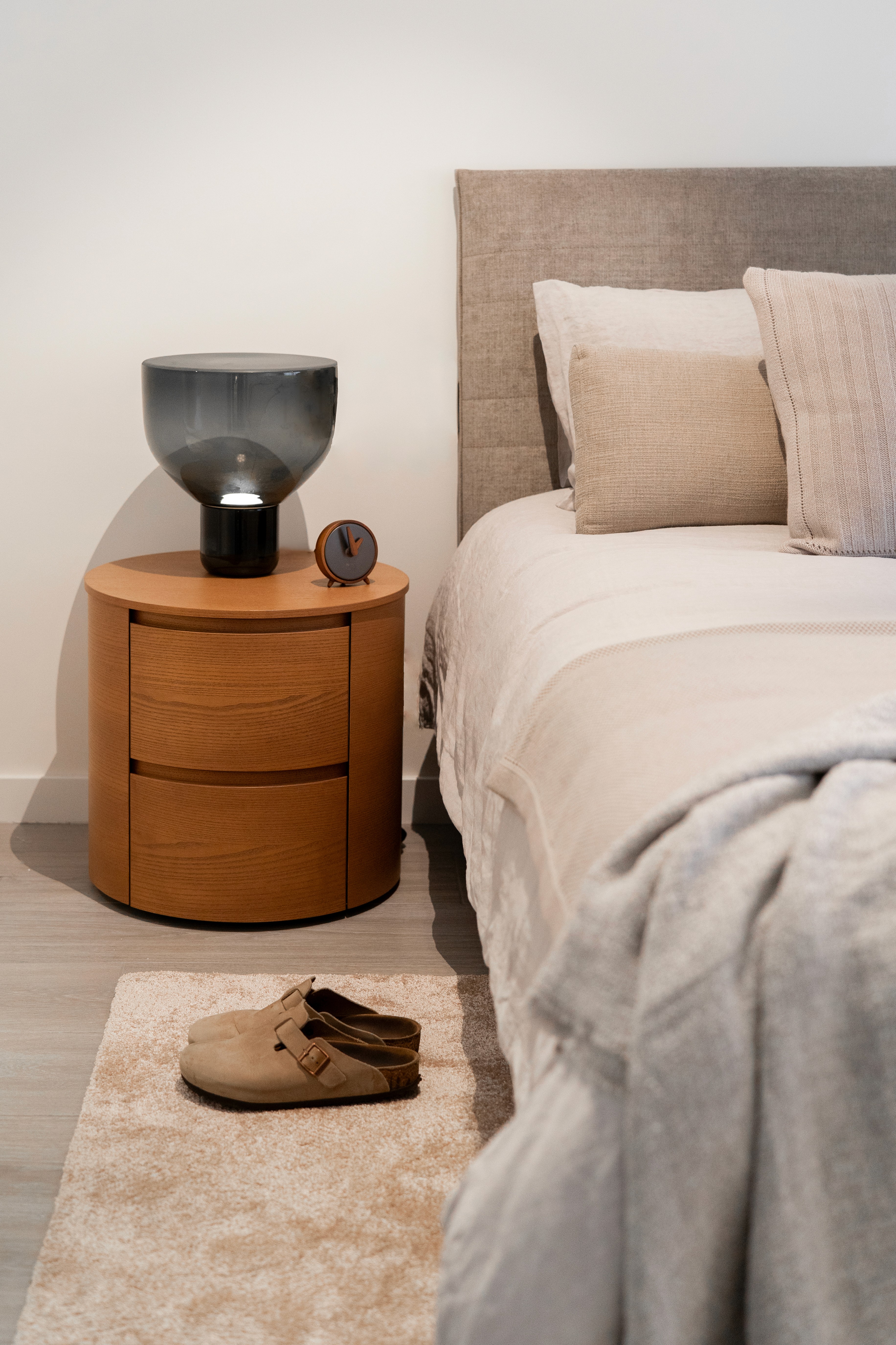 Detalle mesita de noche de madera en dormitorio moderno con tonos neutros grises