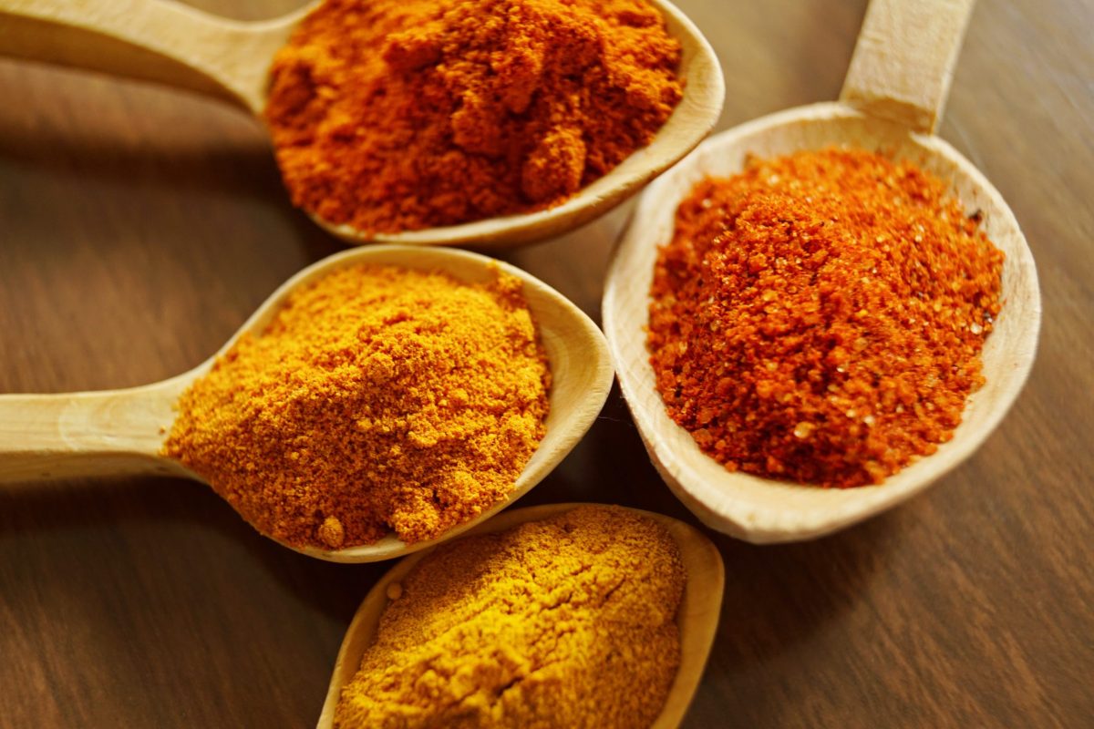 Spices, including turmeric, are displayed on large wooden spoons.