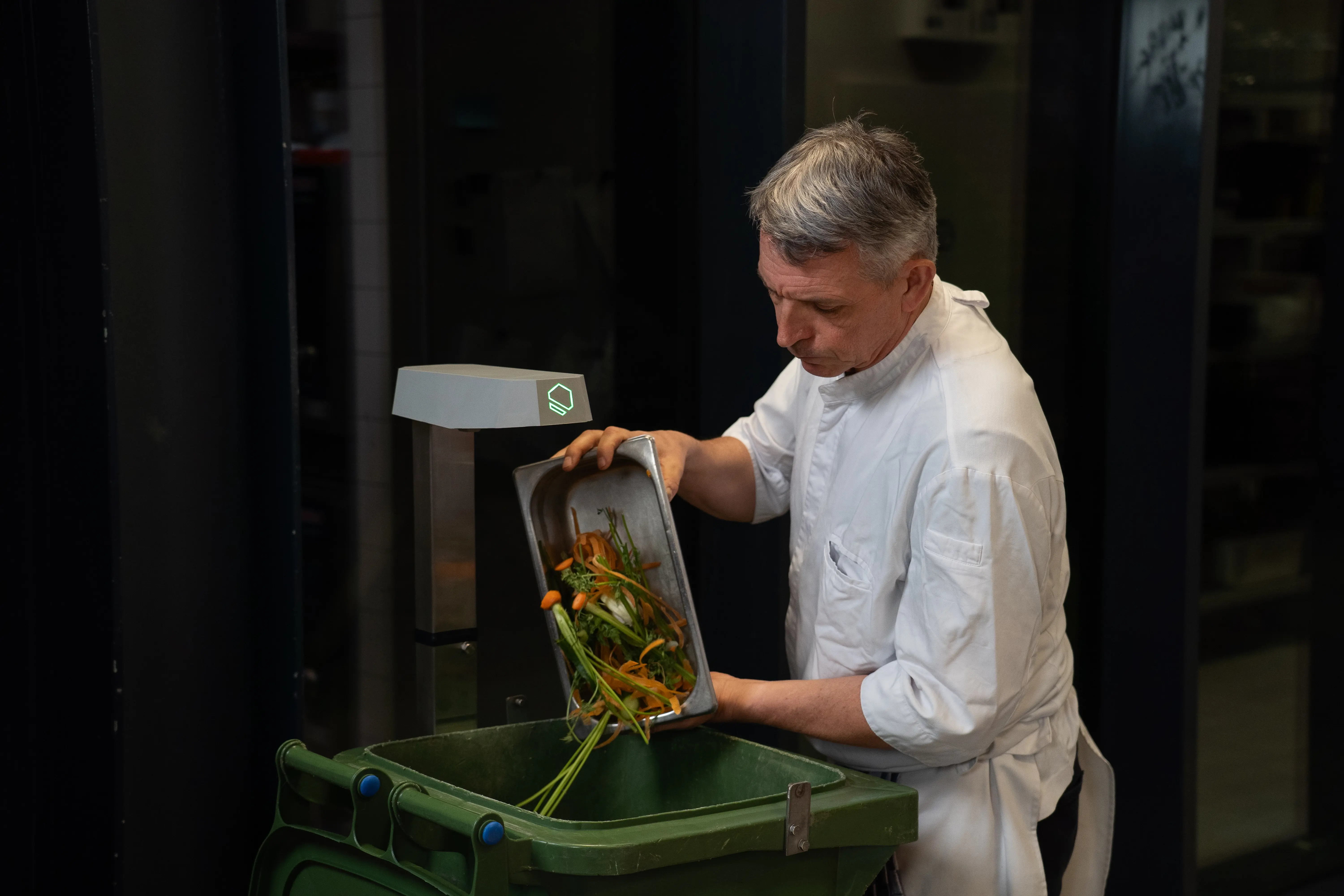 Chef tossing food waste into a bin tracked by the KITRO TARE