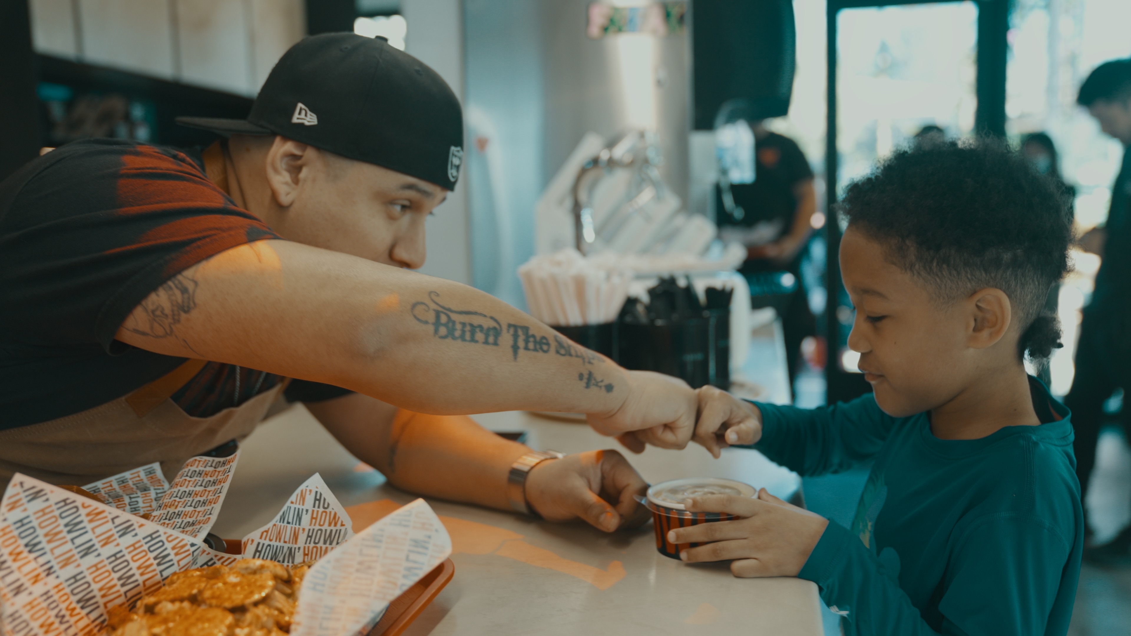 Chef from Howlin Rays in Pasadena California giving child a container of food. 