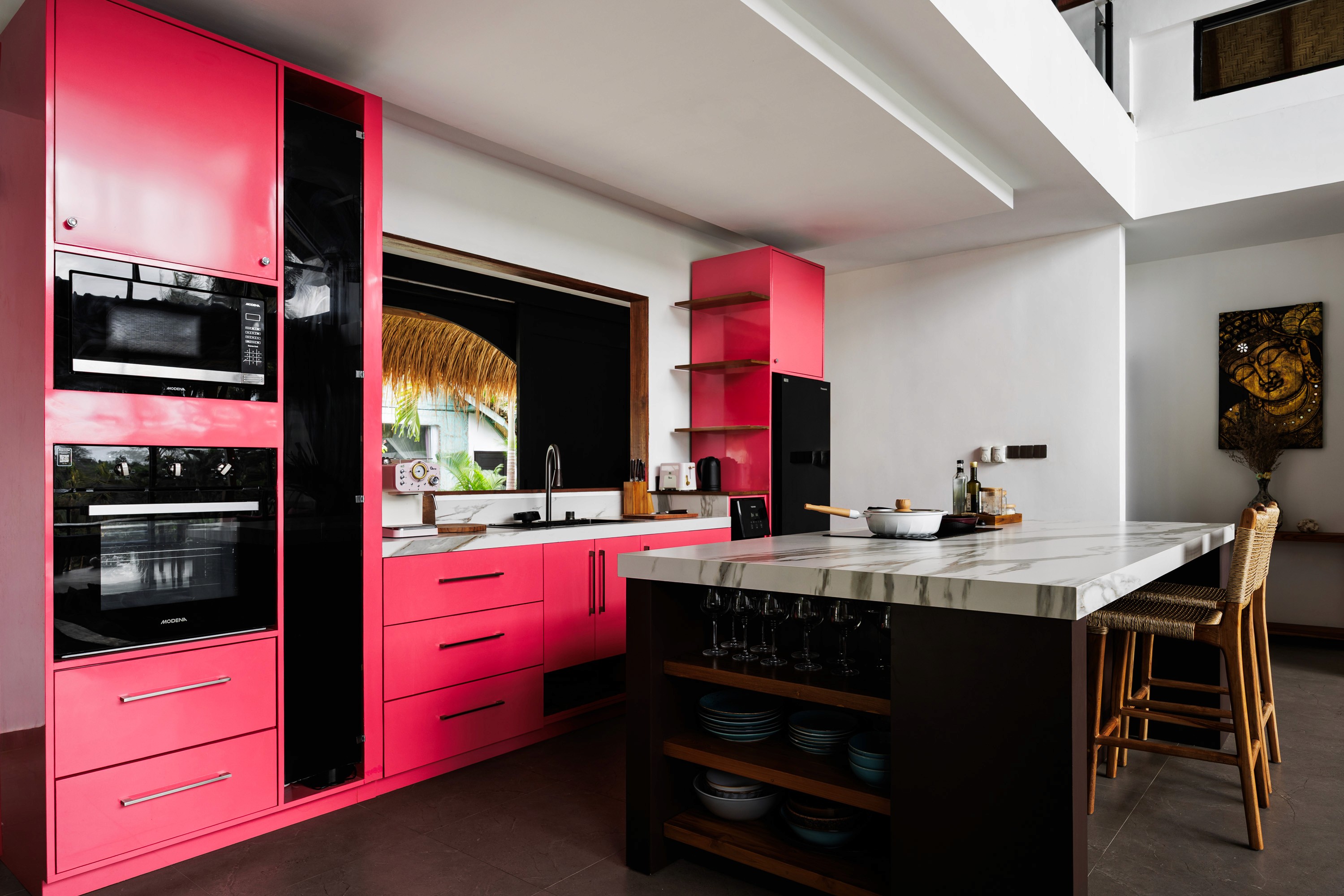 Modern kitchen with bold pink cabinetry, marble island, and open layout.