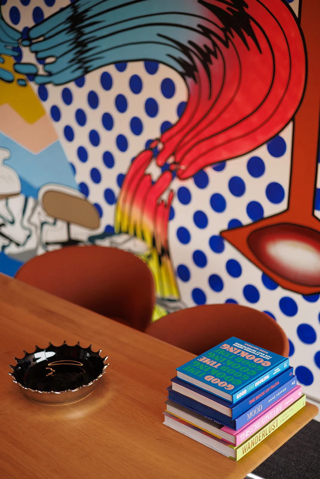 Close-up of colorful books and a decorative dish on an orange desk