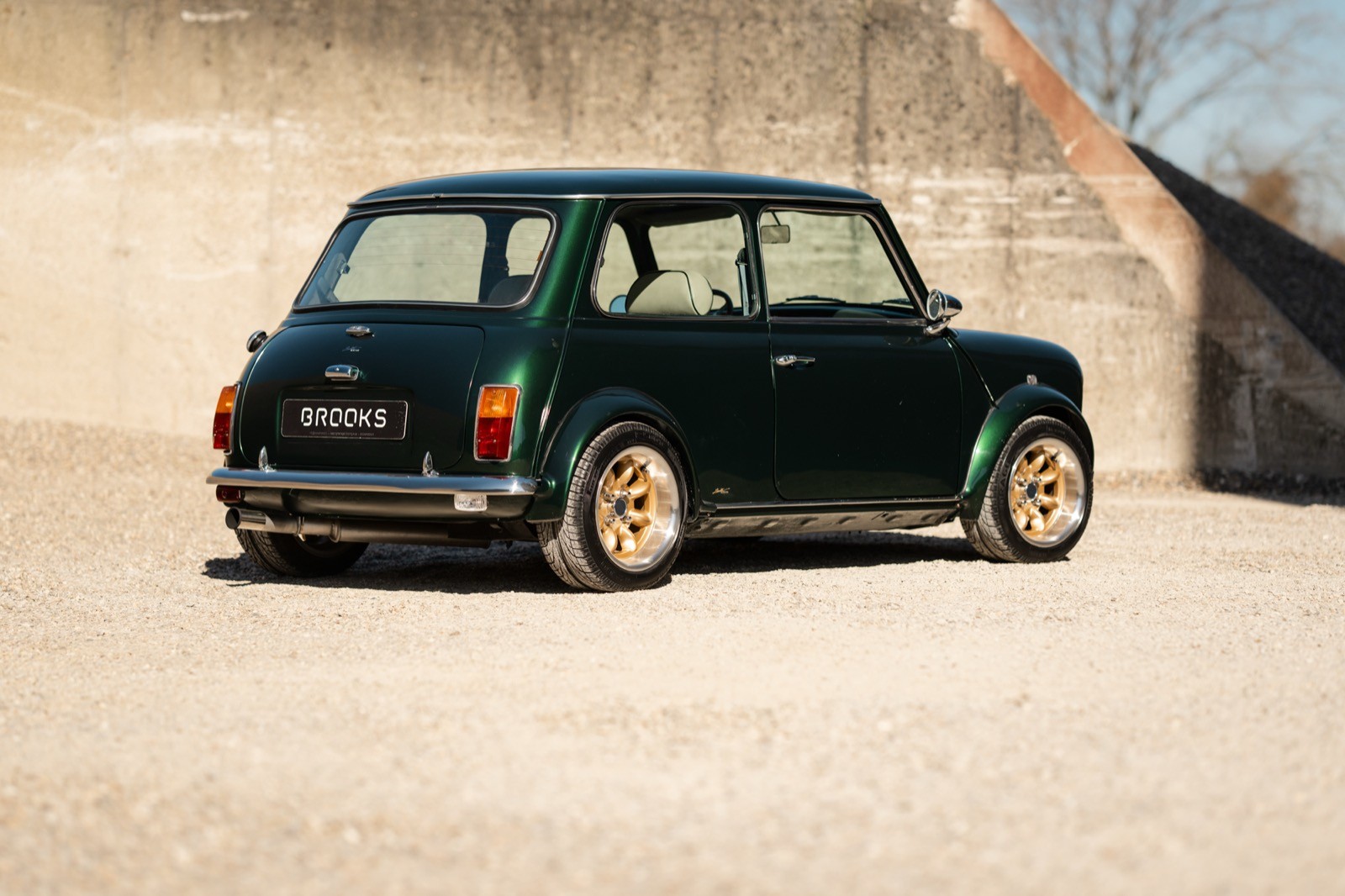 A small, green and black vehicle parked on a sandy surface, with a warm sunset lighting the scene.