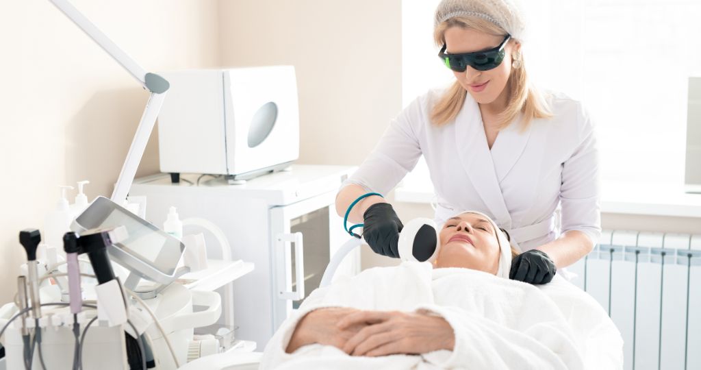 Laser cosmetic clinic professional performing facial treatment on a patient.