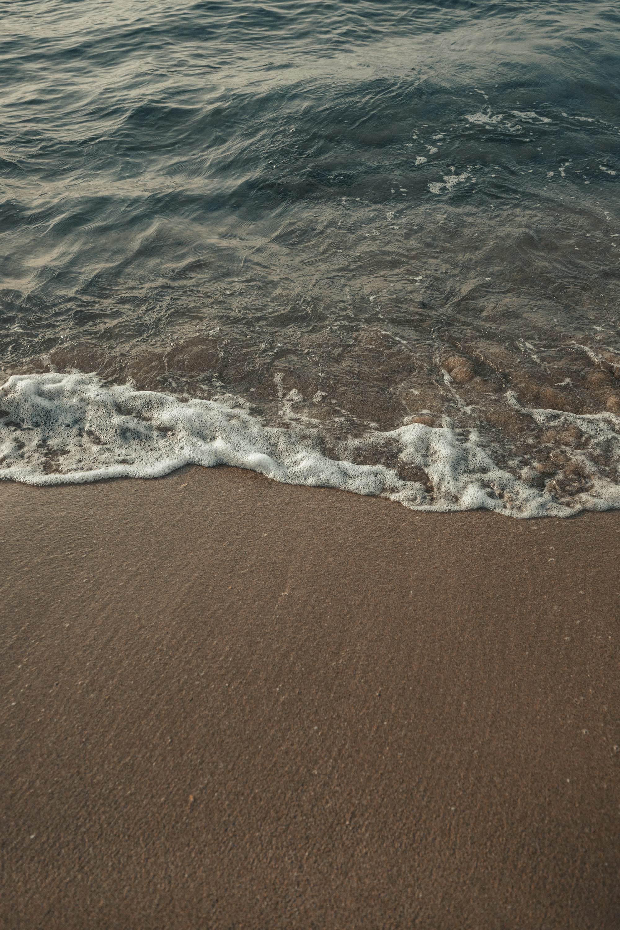 Waves breaking along a sandy shoreline. Photo by Adam Neumann / Unsplash.