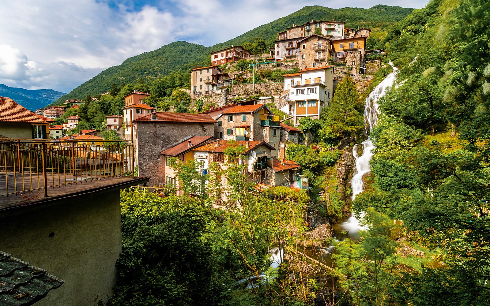 Hillside village with waterfall near Lake Como on public tour route.