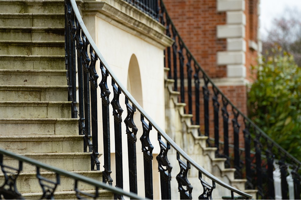 Stone staircase with wrought iron railing at a traditional United Kingdom townhouse, reflecting layered structuring and protection within family trust arrangements.