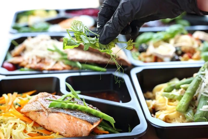 A chef plating fresh meals into prep containers