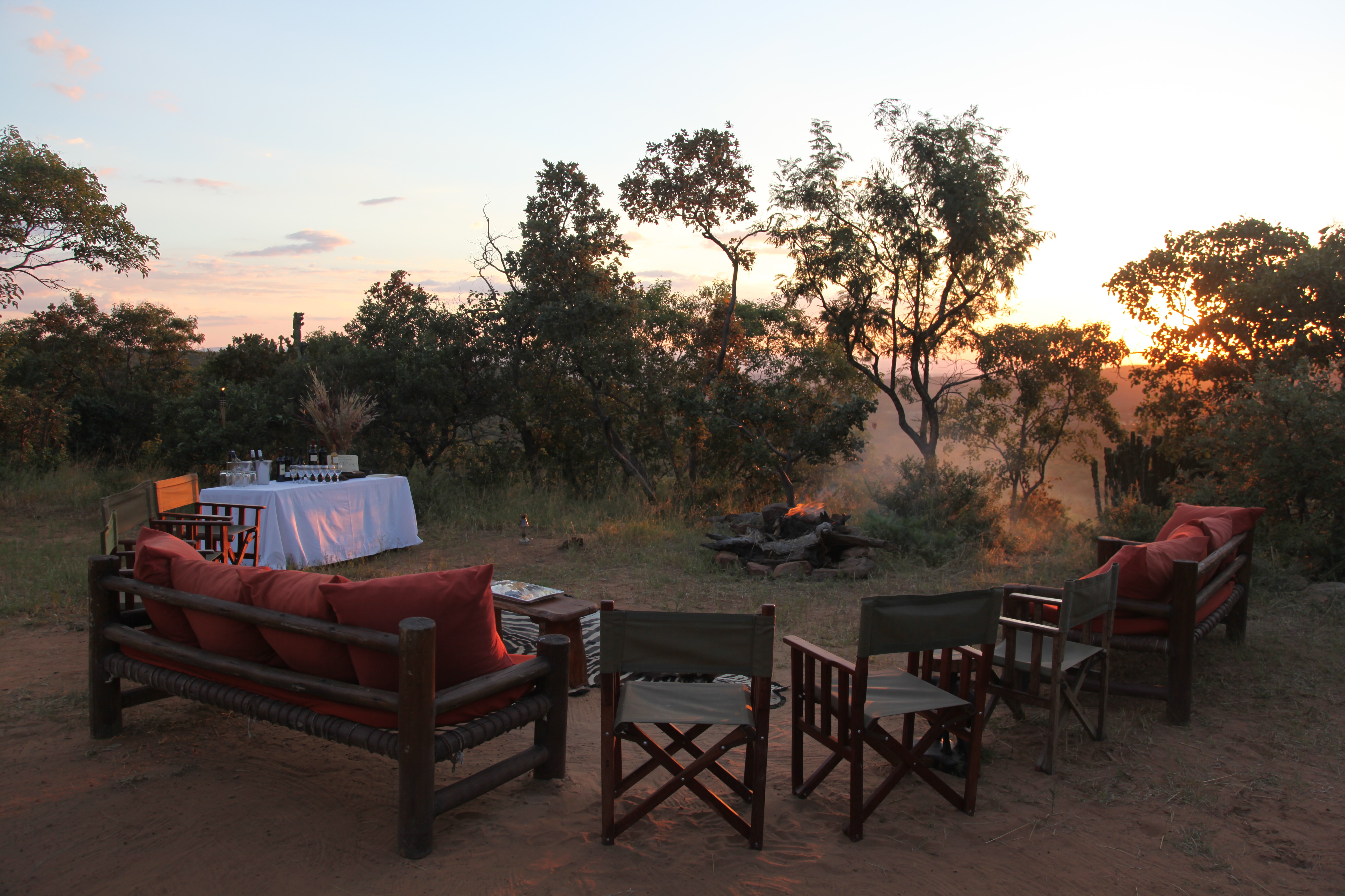 Grupp av ryttare på ridresa i Afrika galopperar över Serengetis vidsträckta slätter medan damm och gnuhjordar rör sig över horisonten under the great migration.