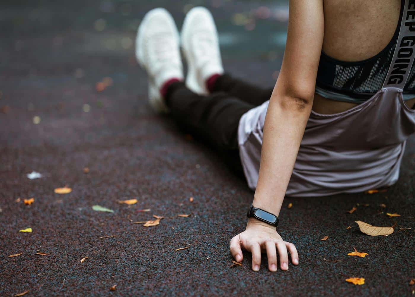 Woman in fitness clothes sitting on the ground resting