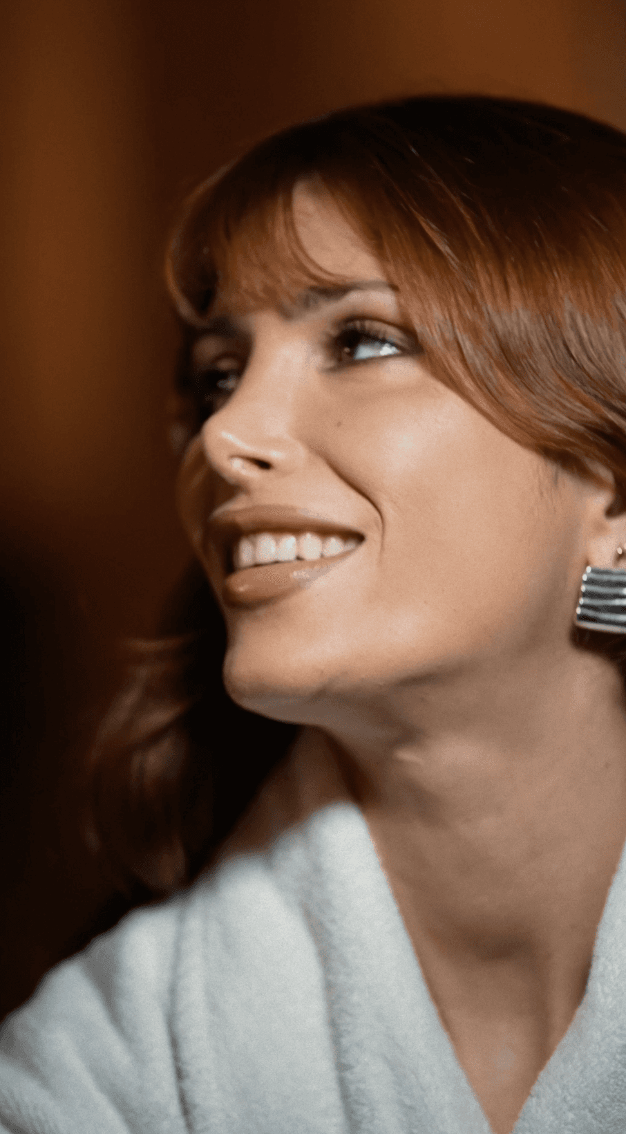 Bride sitting on ground against wall, groom standing nearby
