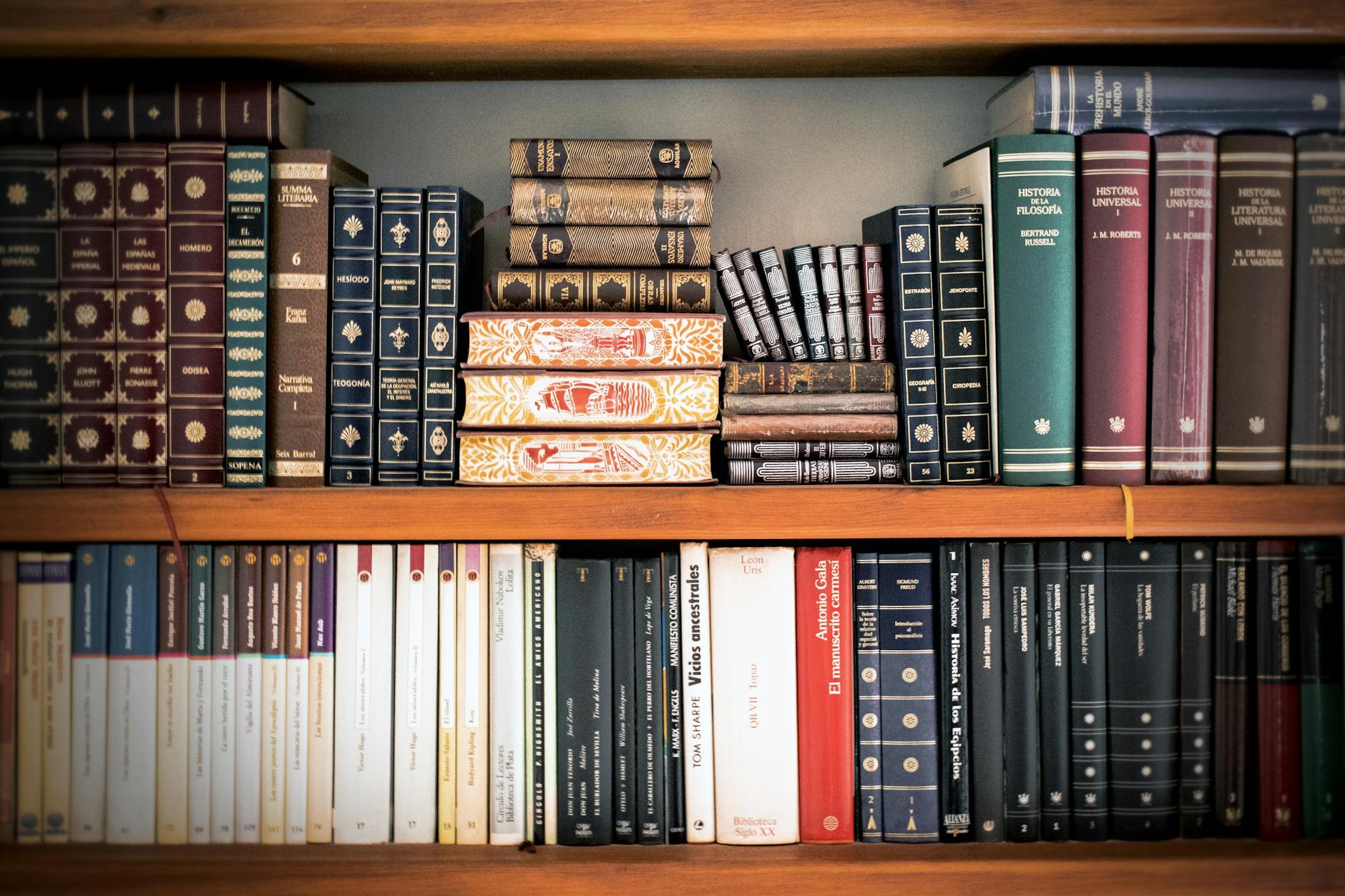 A hand placing a vibrant narrative storybook on top of a stack of dull, grey hardcover textbooks.