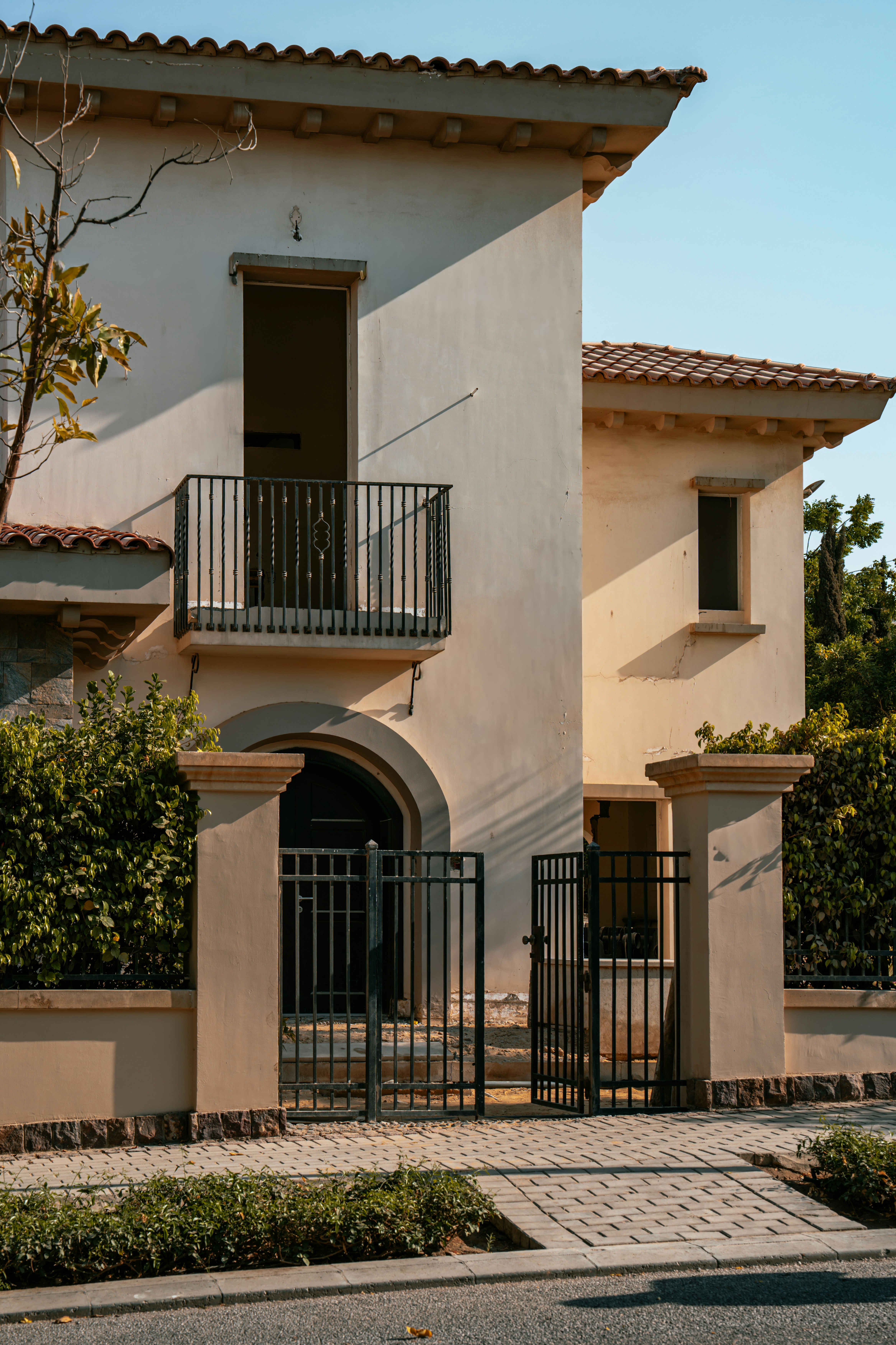 A beige stucco house with a balcony and gate.