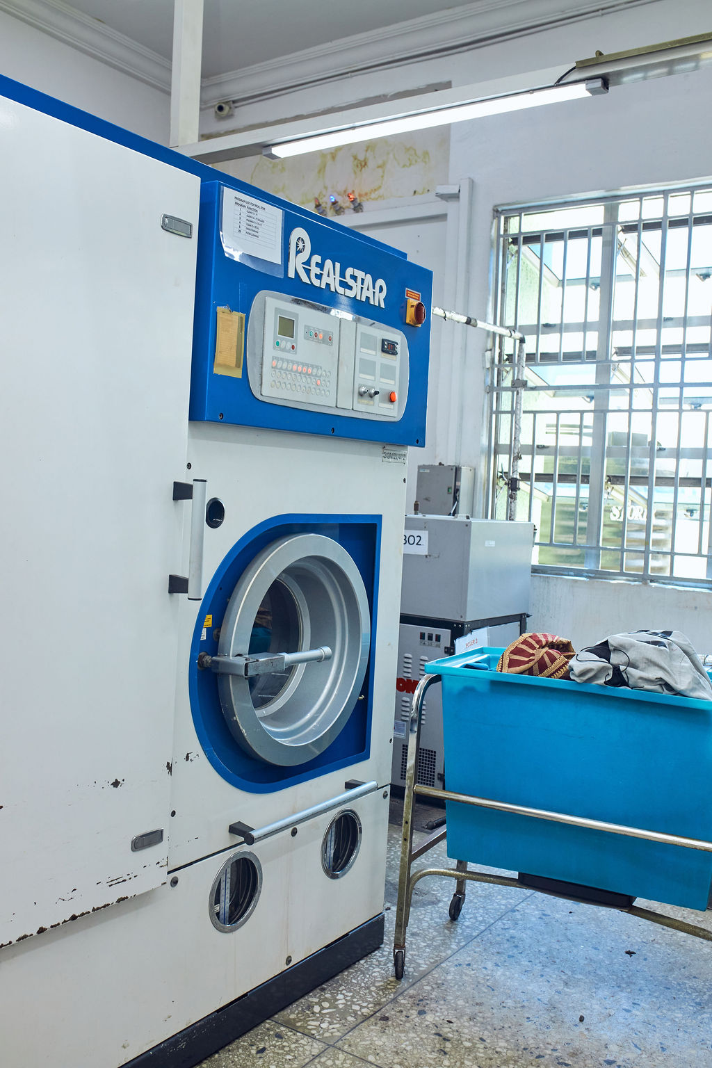 white and teal steam clothes iron plugged on ironing board