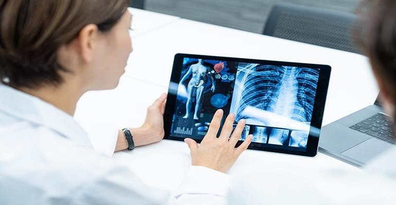 A woman looking at an x-ray on a tablet