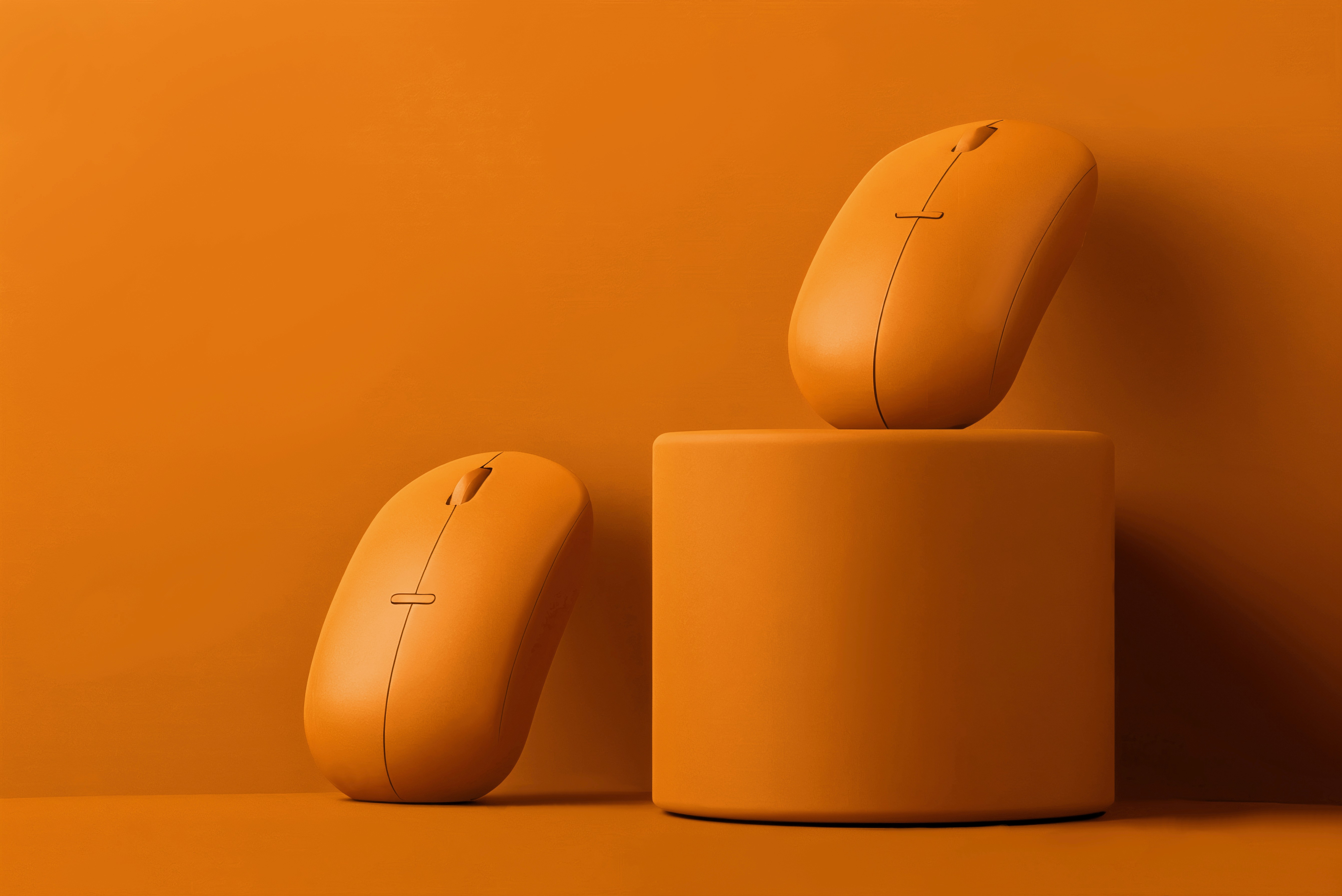 Two orange computer mice displayed on and beside a matching podium.
