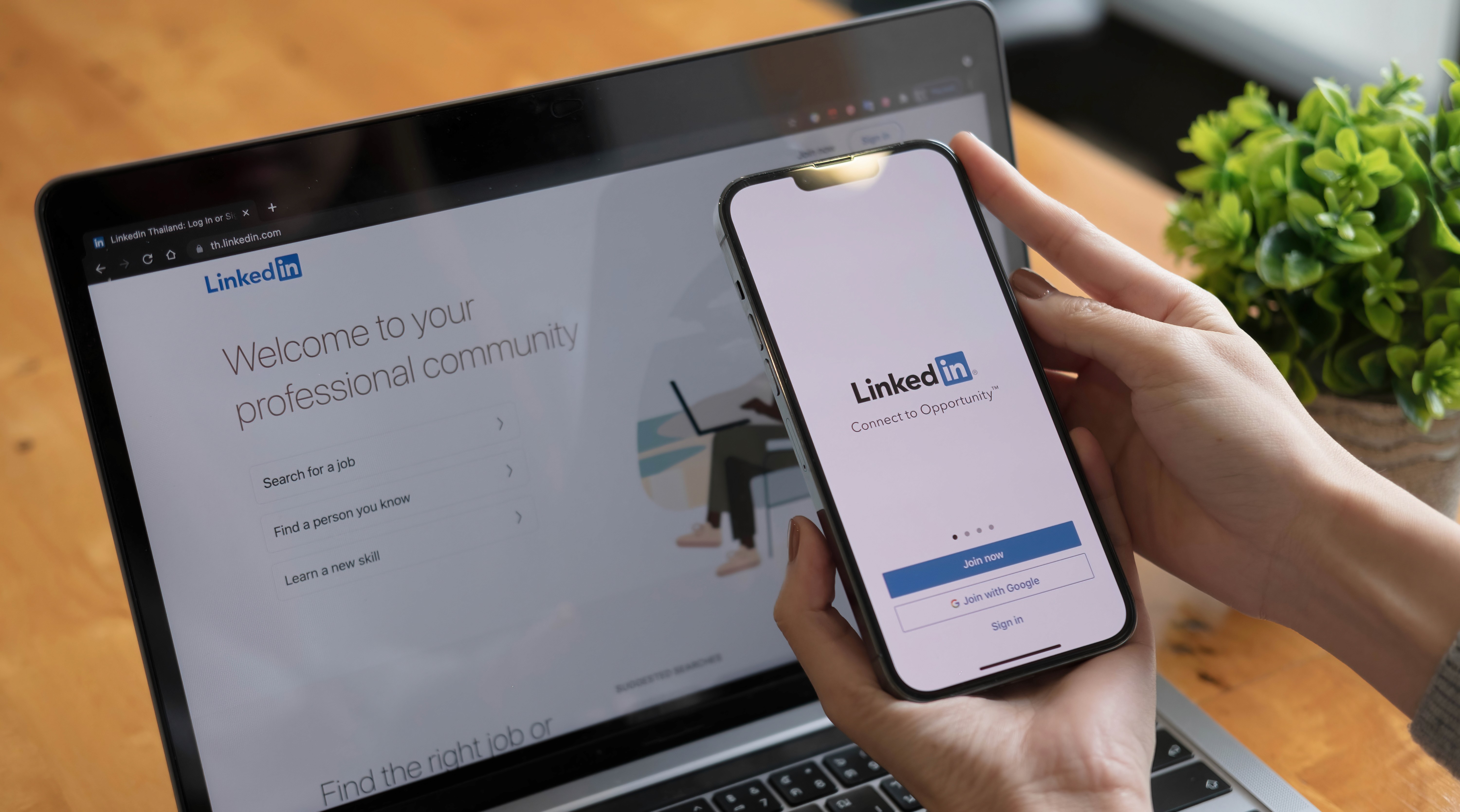 Smartphone zeigt LinkedIn-App mit Laptop im Hintergrund, repräsentiert digitales Employer Branding und Social-Media-Beratung