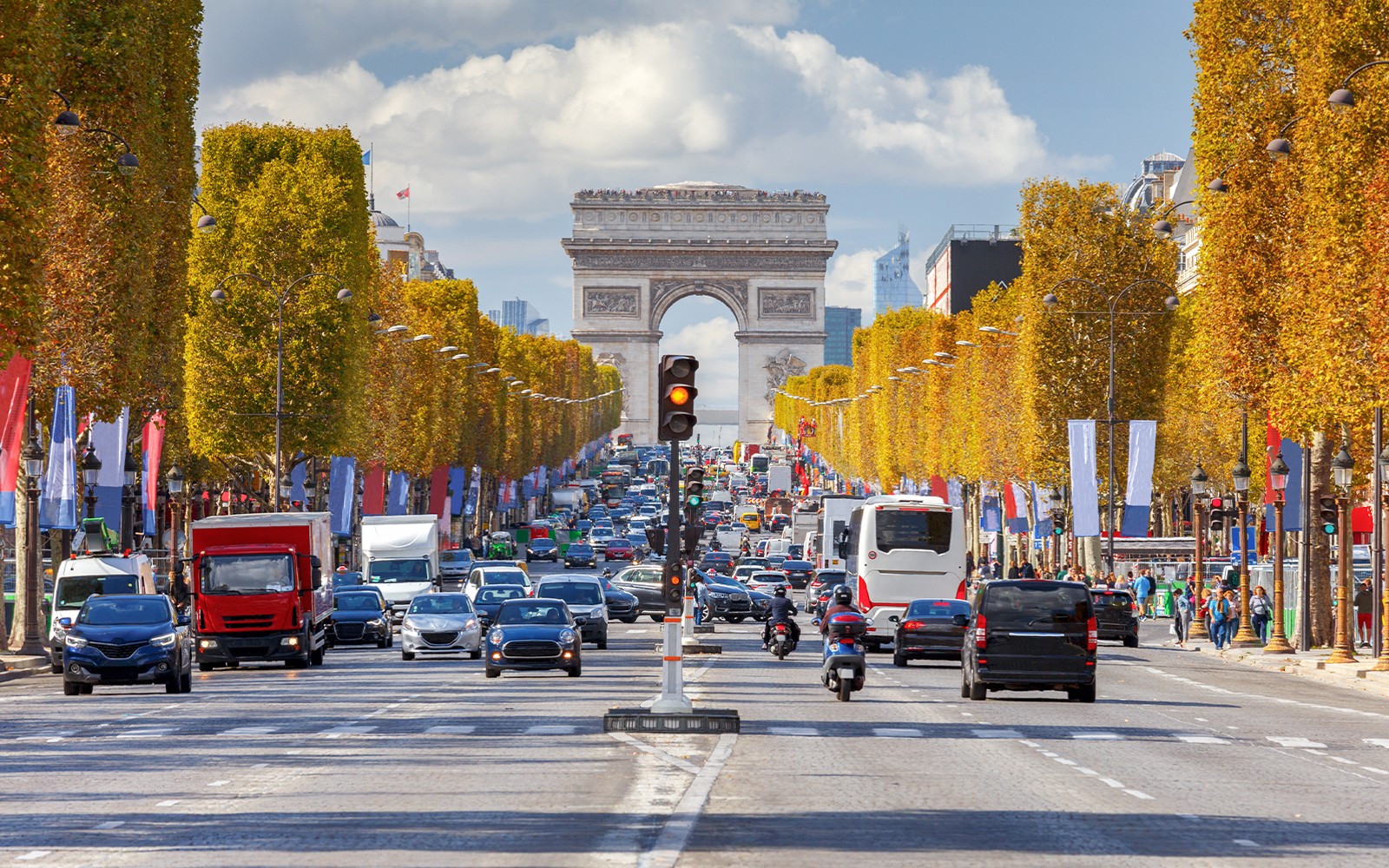 Trafic pe Avenue Champs Elysees cu Arcul de Triumf din Paris.