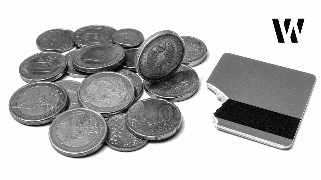 Euro coin cluster mid-fall on white surface, broken card beside it, overhead studio lighting