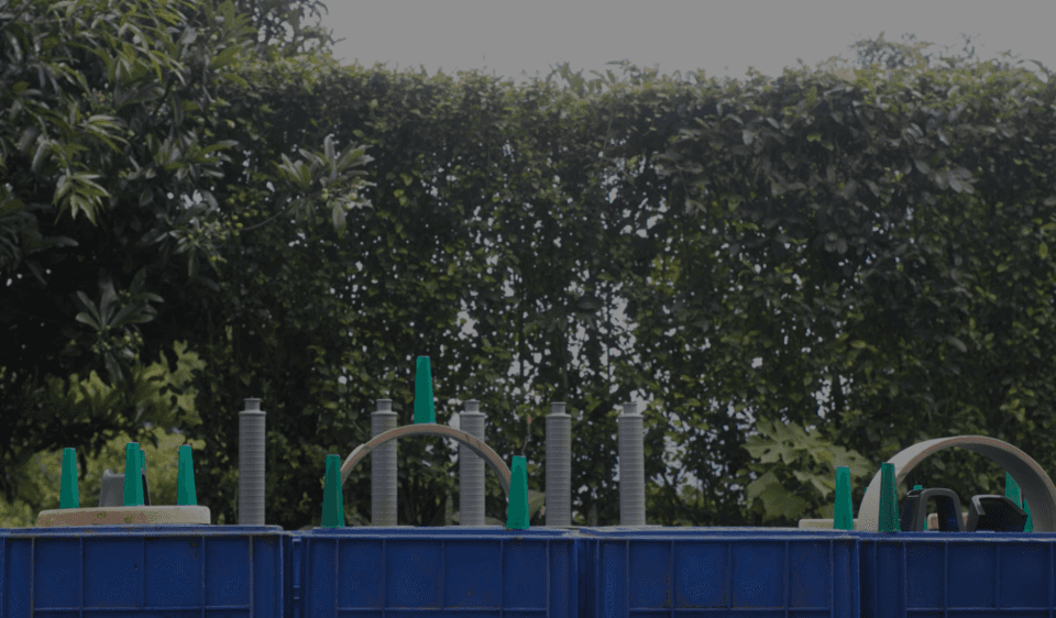 Entorno exterior natural con seto verde frondoso y objetos de juego o construcción con conos verdes