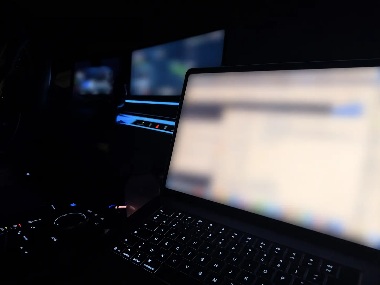 Laptop met meerdere onleesbaar gemaakte werkvensters in een donker auto-interieur.