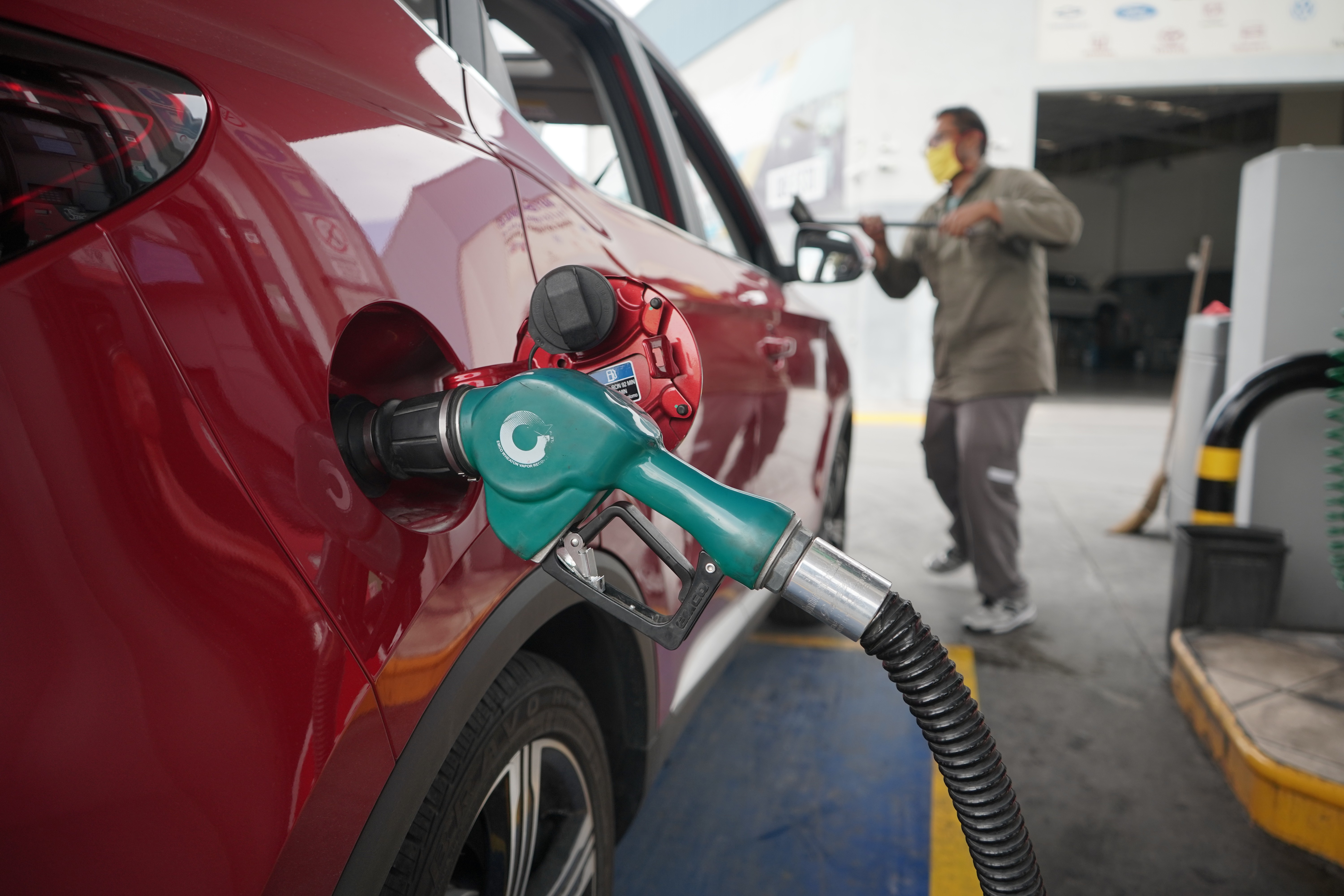 A serene outdoor seating area with two chairs, surrounded by lush greenery and a glassed-in structure.